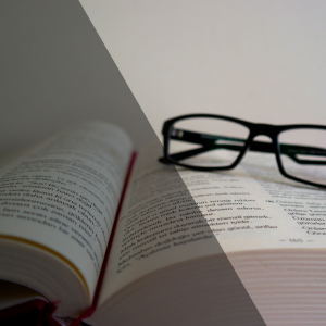Open book with glasses resting on the pages, split diagonally into light and dark, symbolizing contrast.