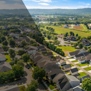Aerial view of a suburban neighborhood with modern homes and green hills in the background, representing steady housing market growth.
